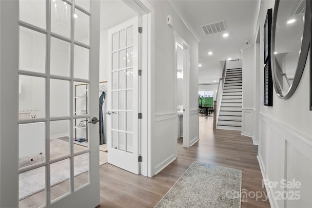 corridor featuring a decorative wall, stairs, visible vents, and wood finished floors