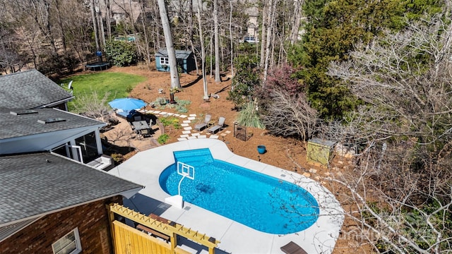 view of swimming pool with a storage unit, an outbuilding, a trampoline, a fenced in pool, and a patio area