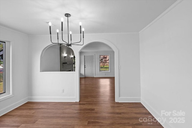 unfurnished dining area with wood finished floors, plenty of natural light, a chandelier, and crown molding