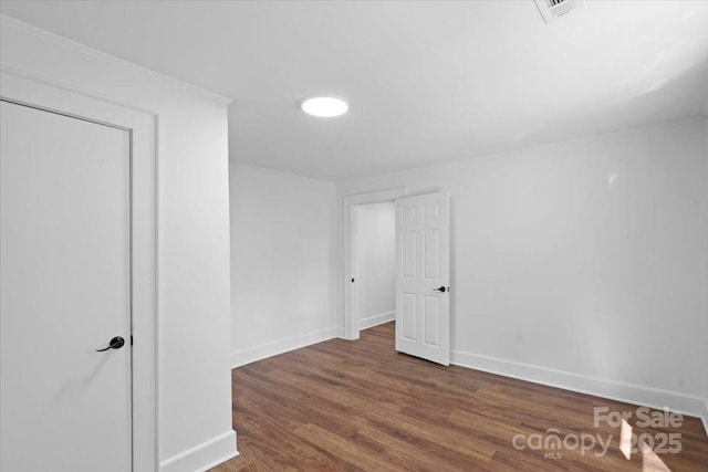 spare room featuring baseboards, wood finished floors, and ornamental molding