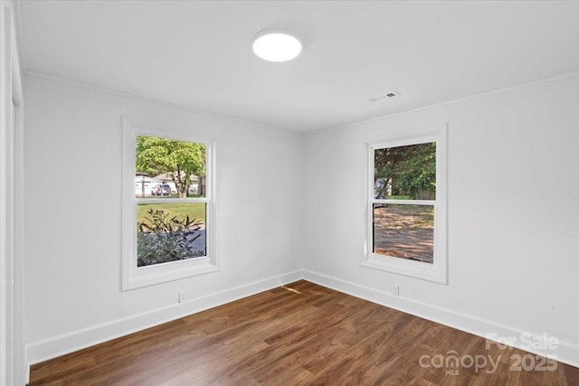 unfurnished room with dark wood-type flooring, plenty of natural light, and baseboards