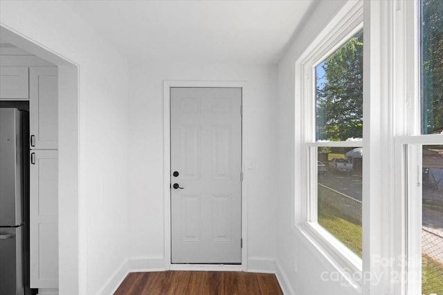 doorway to outside featuring baseboards and dark wood-style flooring