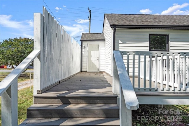 entrance to property with a wooden deck and a shingled roof