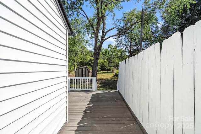 wooden terrace with a storage shed, fence, and an outdoor structure