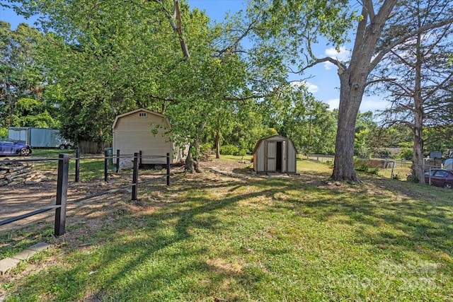 view of yard featuring an outbuilding, a shed, and fence