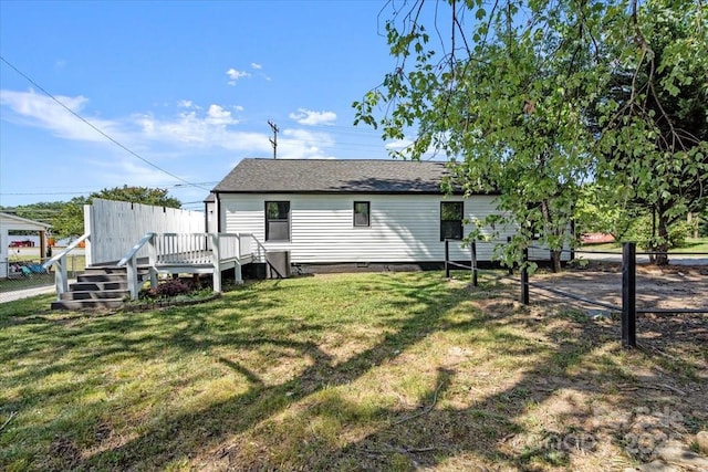 rear view of house with fence, a yard, roof with shingles, a wooden deck, and crawl space