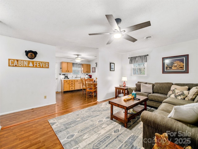 living room featuring visible vents, baseboards, a textured ceiling, and dark wood-style flooring