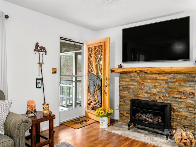 living area featuring a stone fireplace and wood finished floors