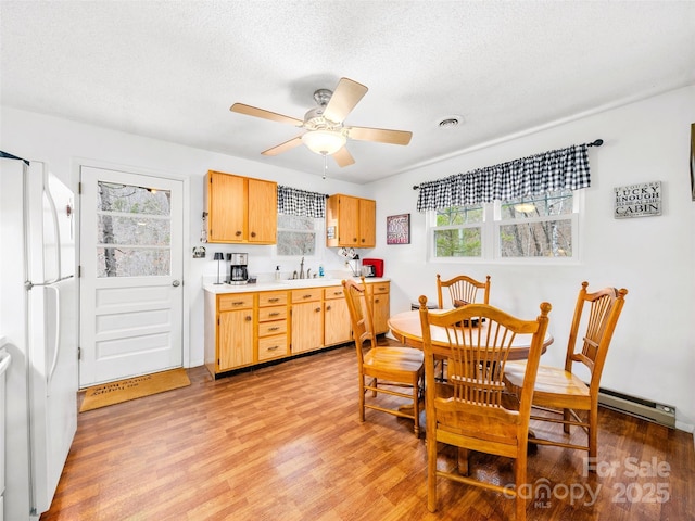 kitchen featuring visible vents, a sink, freestanding refrigerator, light wood-style floors, and light countertops