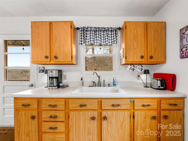 kitchen with a textured ceiling, light countertops, and a sink