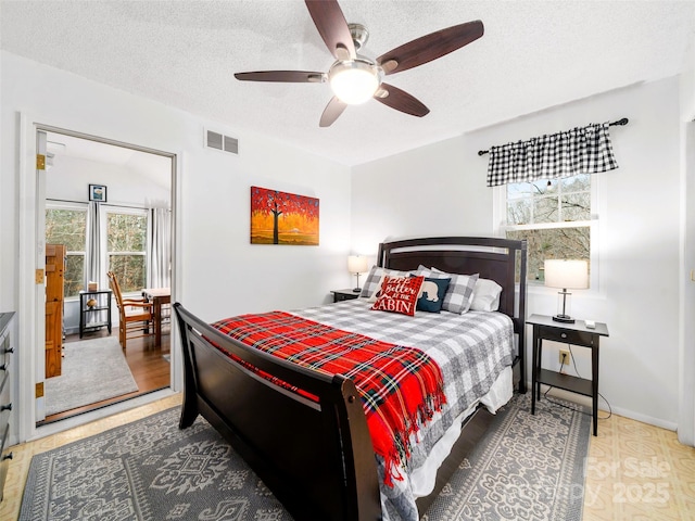 bedroom featuring baseboards, a ceiling fan, visible vents, and a textured ceiling