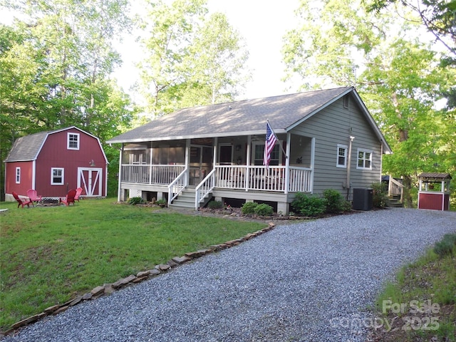 view of front facade featuring an outbuilding, central AC unit, a sunroom, and a front lawn