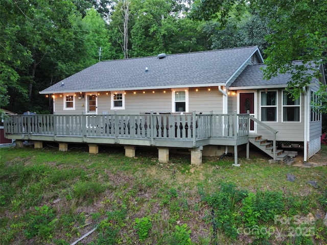 back of property featuring roof with shingles and a deck