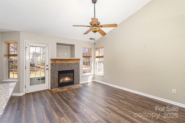 unfurnished living room featuring dark wood finished floors, lofted ceiling, a fireplace, and baseboards