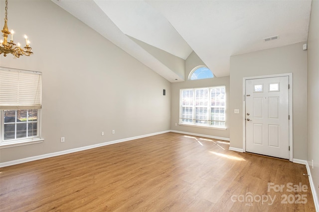 foyer entrance with a notable chandelier, visible vents, plenty of natural light, and light wood-style floors