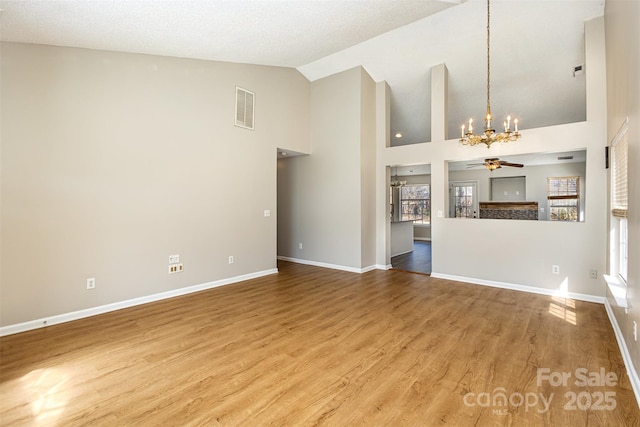 unfurnished living room featuring visible vents, high vaulted ceiling, ceiling fan with notable chandelier, wood finished floors, and baseboards