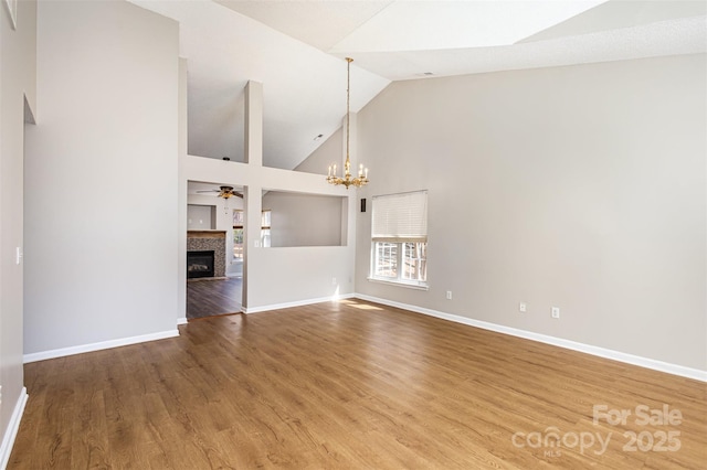 unfurnished living room featuring a tiled fireplace, baseboards, and wood finished floors