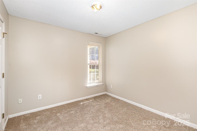 spare room featuring baseboards, carpet, visible vents, and a textured ceiling