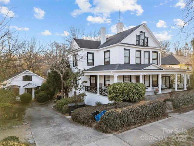 view of front of property featuring a porch, a chimney, and a shingled roof