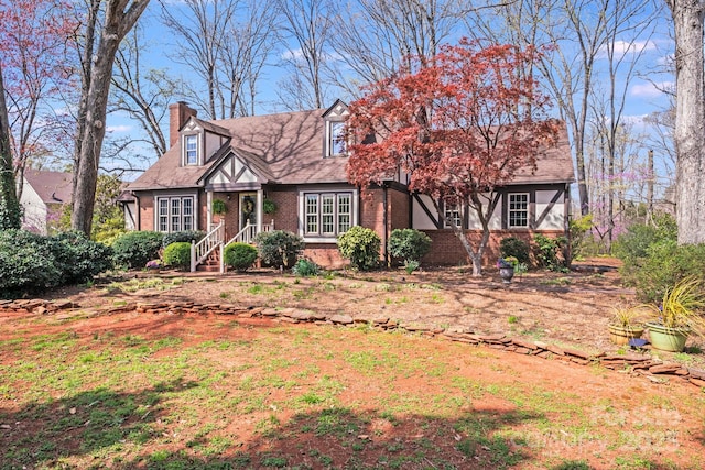 tudor home with brick siding and a chimney