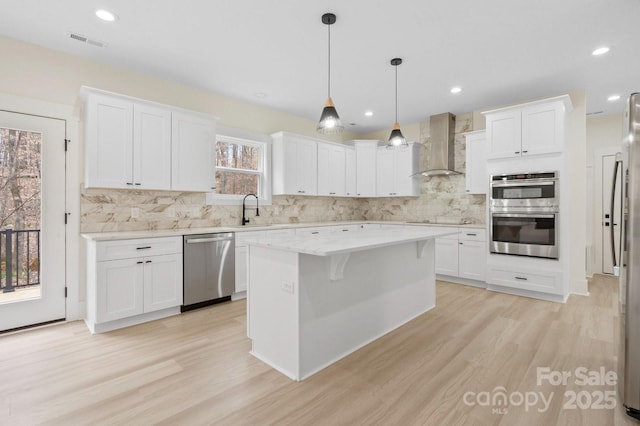 10405 Briarhurst Pl Unit 18, Mint Hill, NC 28227 - kitchen featuring stainless steel appliances, wall chimney exhaust hood, light wood-style floors, a center island, and decorative backsplash