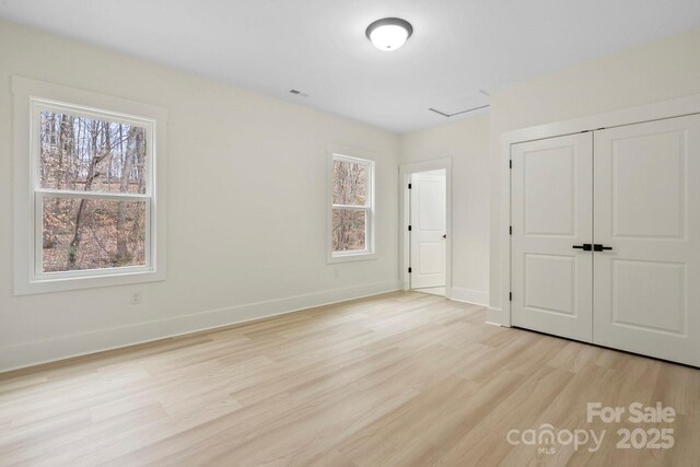 10405 Briarhurst Pl Unit 18, Mint Hill, NC 28227 - unfurnished bedroom featuring light wood finished floors, multiple windows, a closet, and baseboards