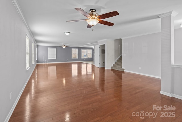 unfurnished living room featuring hardwood / wood-style floors, stairway, crown molding, baseboards, and ceiling fan