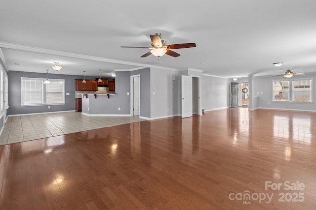 unfurnished living room featuring crown molding, light wood-style flooring, and baseboards