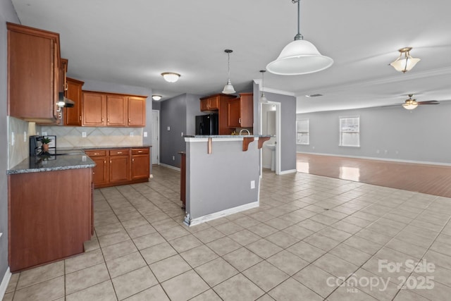 kitchen featuring a kitchen breakfast bar, open floor plan, freestanding refrigerator, a peninsula, and decorative backsplash