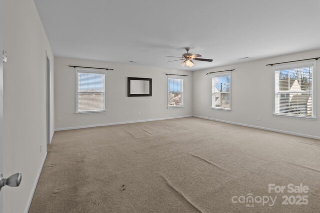 carpeted spare room with ceiling fan and baseboards