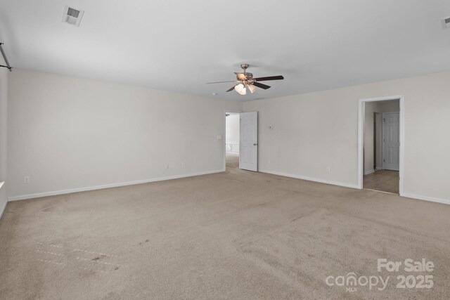 carpeted empty room featuring baseboards, visible vents, and ceiling fan