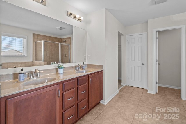 bathroom with a sink, double vanity, a shower stall, and tile patterned floors