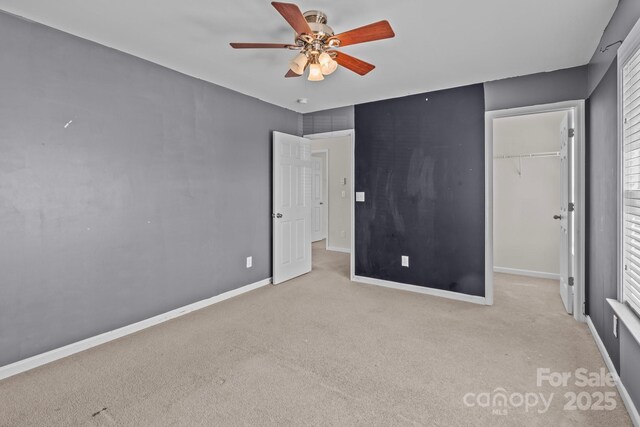 unfurnished bedroom featuring a spacious closet, carpet flooring, baseboards, and a closet