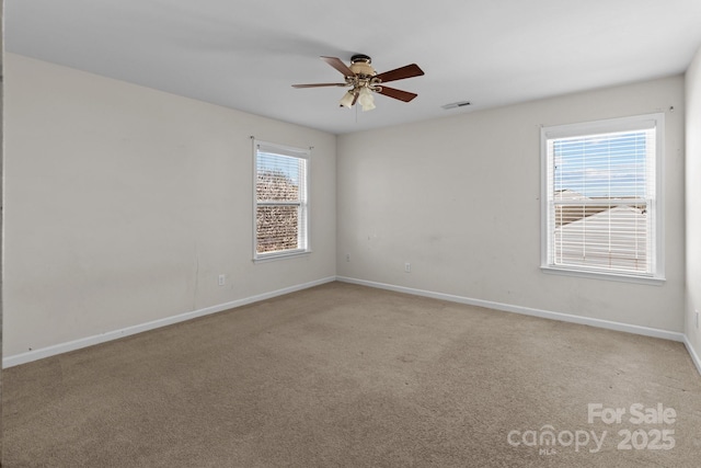 unfurnished room with visible vents, light colored carpet, baseboards, and ceiling fan