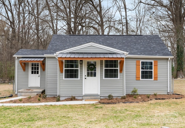 view of front of property featuring roof with shingles, a front lawn, and fence