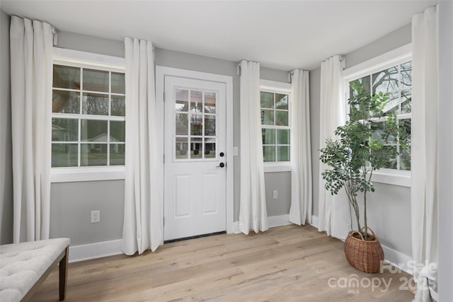 doorway to outside with light wood-style flooring and baseboards