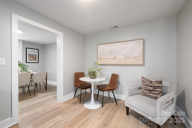 living area featuring light wood-type flooring, baseboards, and visible vents