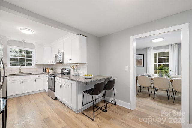 kitchen with a sink, light stone counters, tasteful backsplash, and appliances with stainless steel finishes