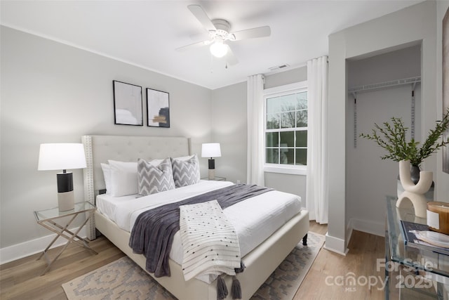 bedroom featuring light wood finished floors, visible vents, and baseboards