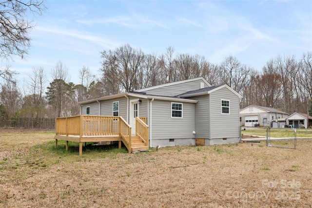 rear view of house with fence, a wooden deck, a lawn, crawl space, and a gate