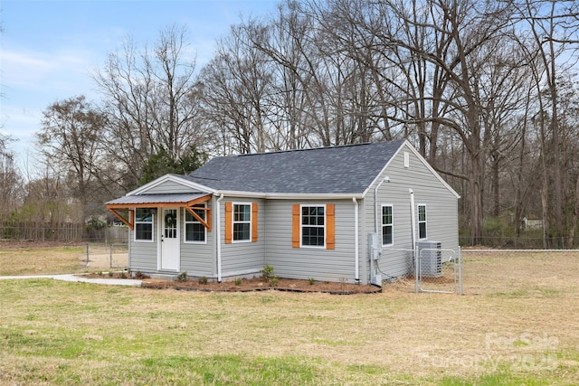 view of front of home featuring a gate, central AC, fence, roof with shingles, and a front yard