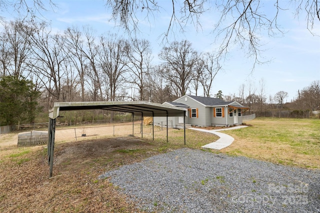 exterior space featuring a carport, driveway, a front lawn, and fence