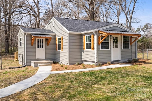 bungalow-style house with roof with shingles, a front lawn, and fence