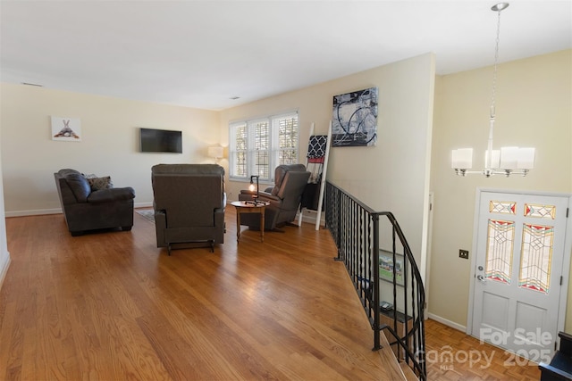 living room with a chandelier, baseboards, and wood finished floors