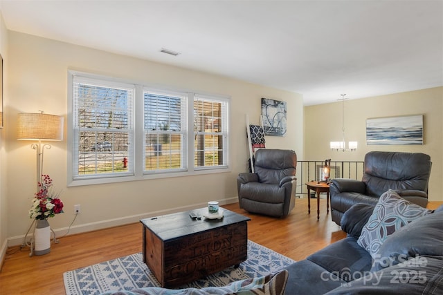 living area featuring an inviting chandelier, baseboards, visible vents, and light wood-type flooring