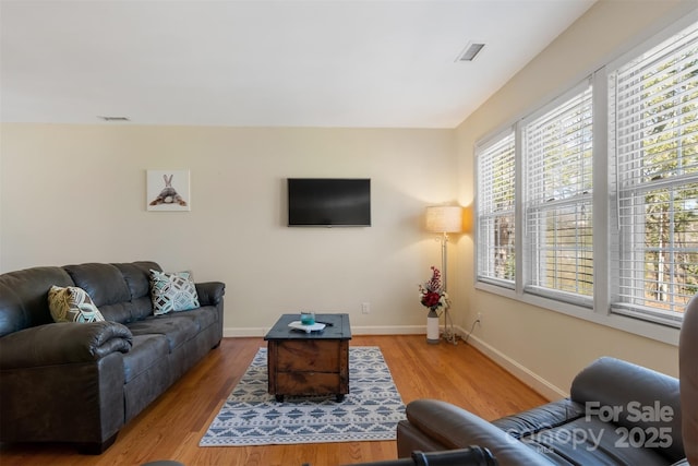 living area featuring visible vents, baseboards, and wood finished floors