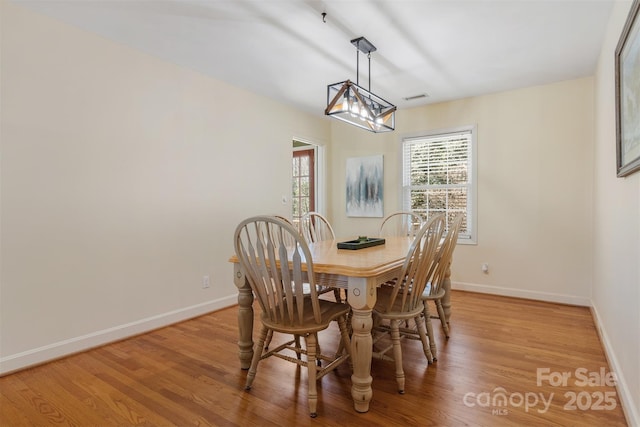 dining area with visible vents, baseboards, light wood-style floors, and an inviting chandelier