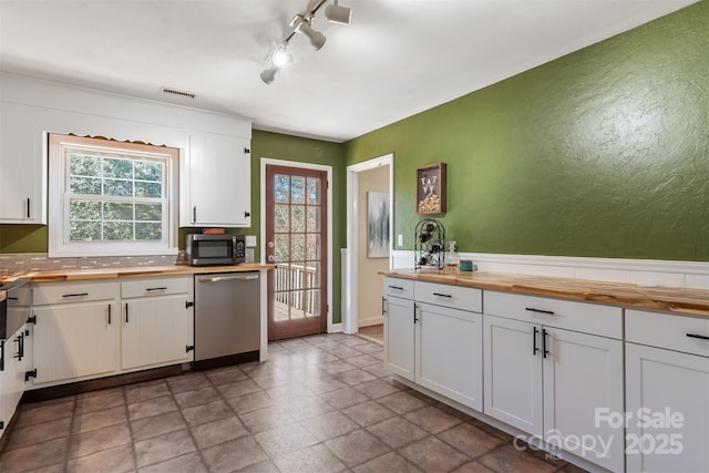 kitchen with white cabinetry, visible vents, stainless steel appliances, and butcher block countertops