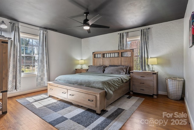 bedroom with visible vents, a ceiling fan, baseboards, and wood finished floors