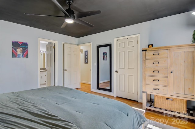 bedroom with a ceiling fan, ensuite bath, and wood finished floors